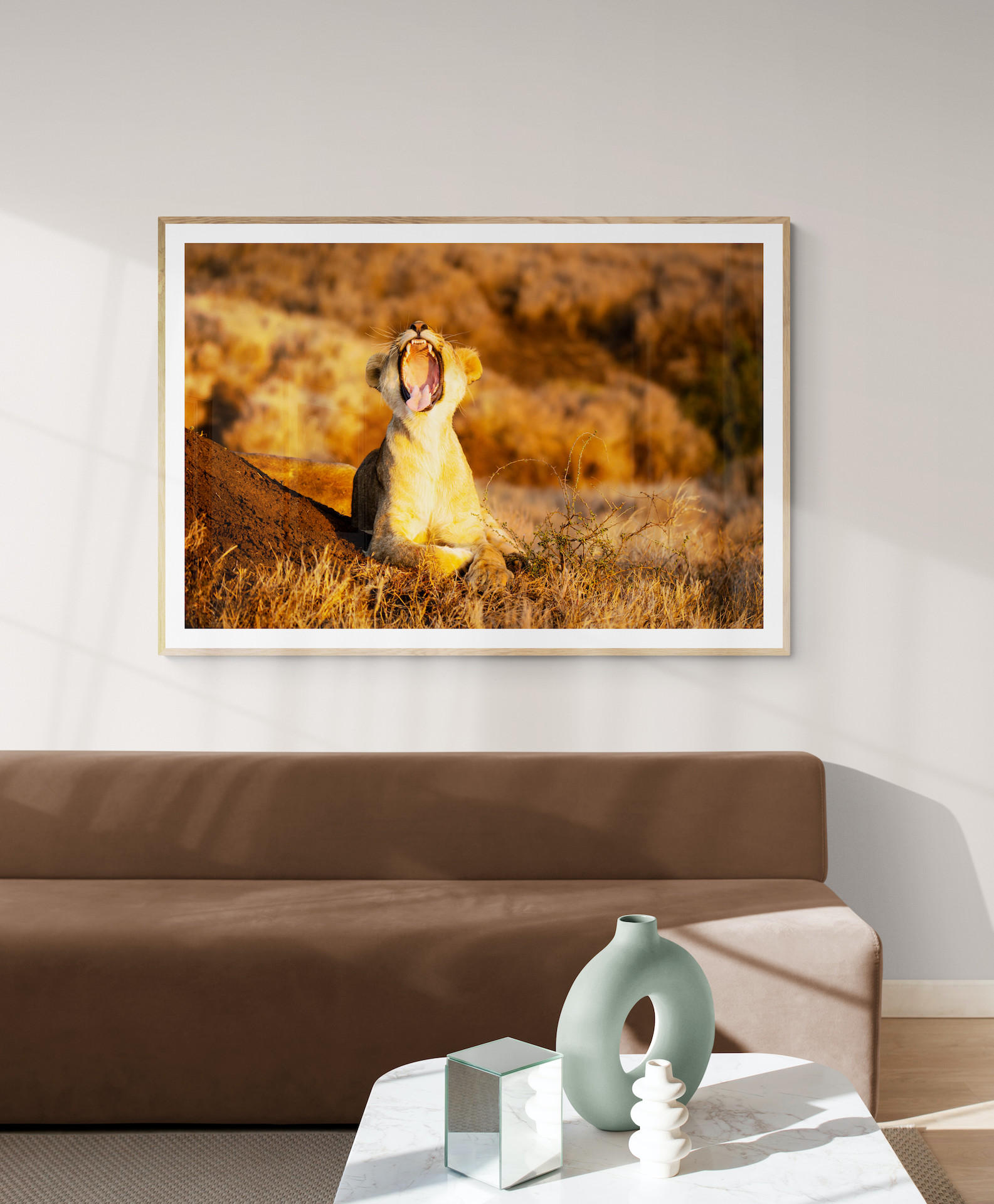An image of a living room with a large photo of a lion yawning in at sunset on the wall