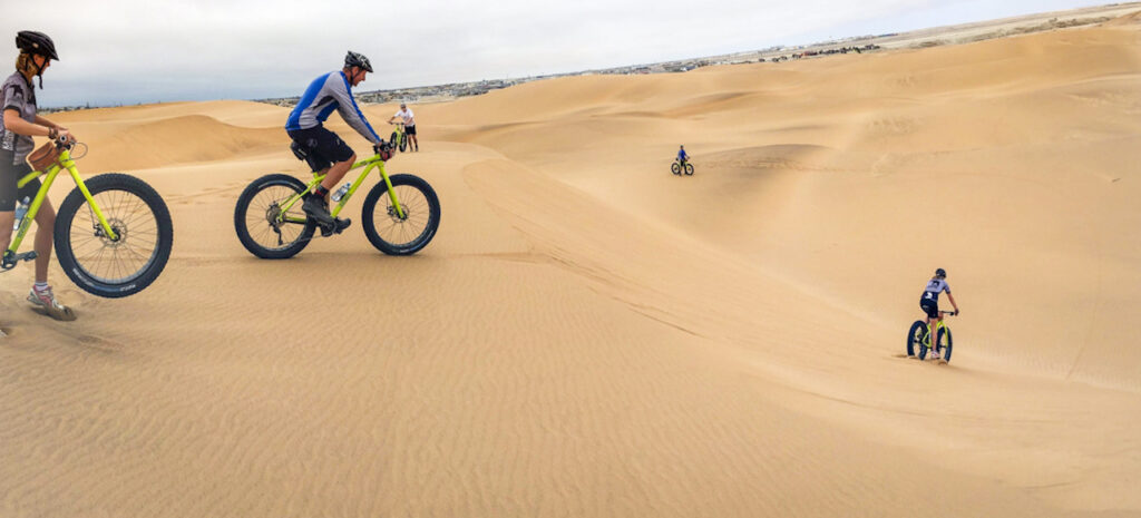 A man and lady cycling down a sand dune in Namibia 