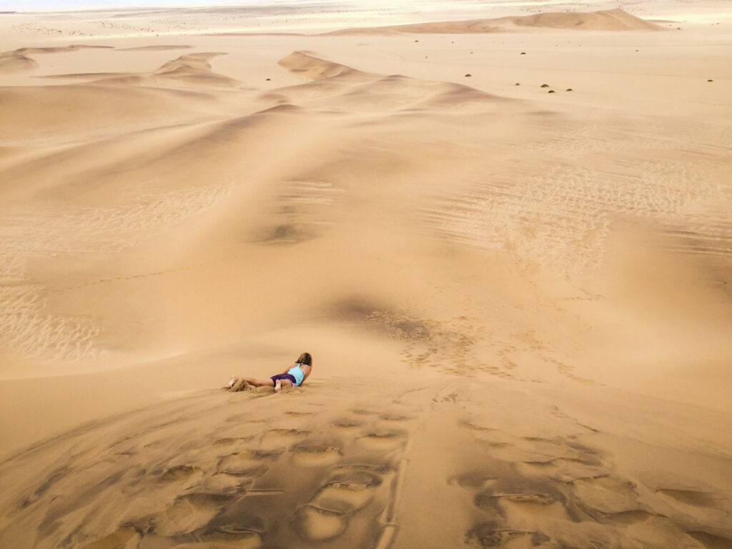 A lady sand boarding down a dune in Namibia 