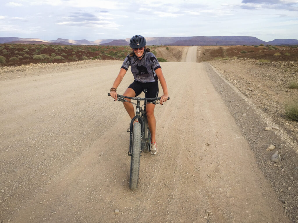 A lady cycling on a gravel road in Palmwag, Namibia 