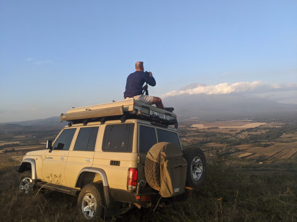 A man sitting on a land cruiser roof 
